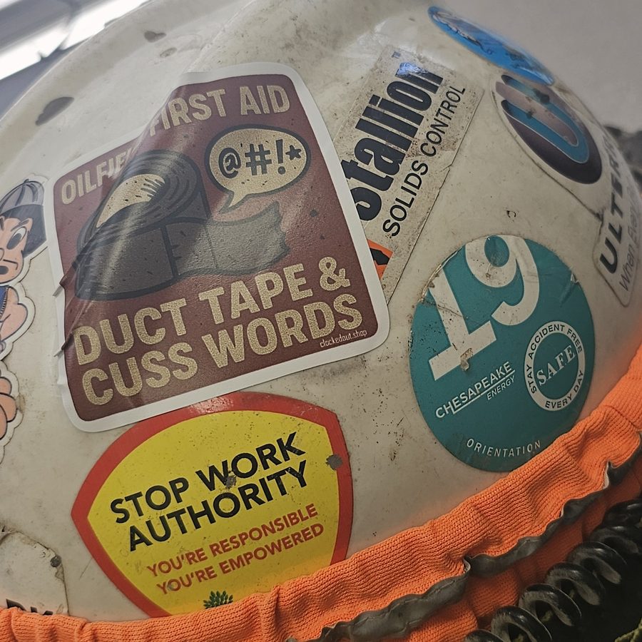 Clocked Out sticker on a real oilfield hard hat